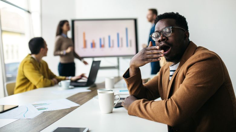 Young male businessman having hard time to listen his colleagues at the business meeting in the modern office.