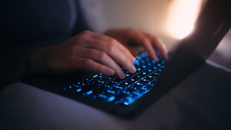 Close up hands of female using laptop in bed at night. 