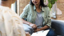 The young adult woman focuses completely on the advice being given by the unrecognizable female therapist.