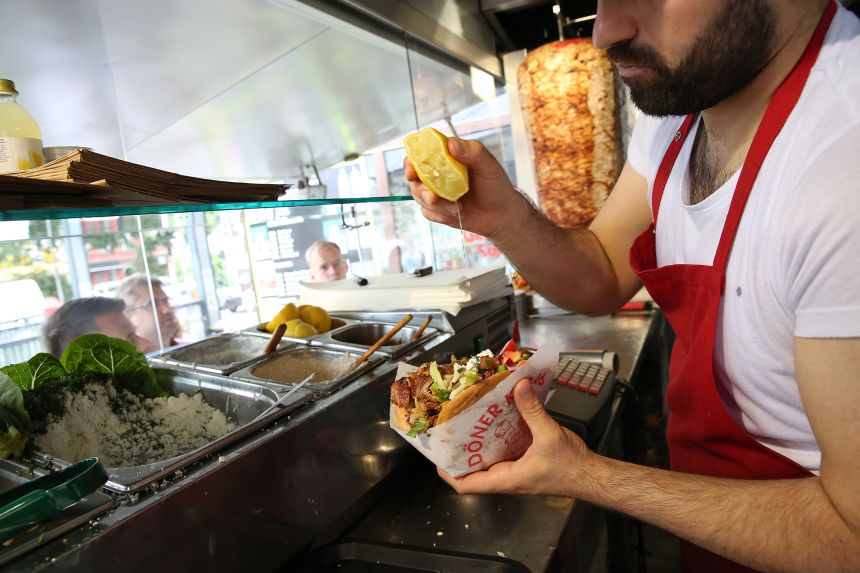 An employee prepares a customer's order at Mustafas Gemüse Kebap in Berlin, Germany. The döner kebab was popularized in Germany by Turkish guest workers.