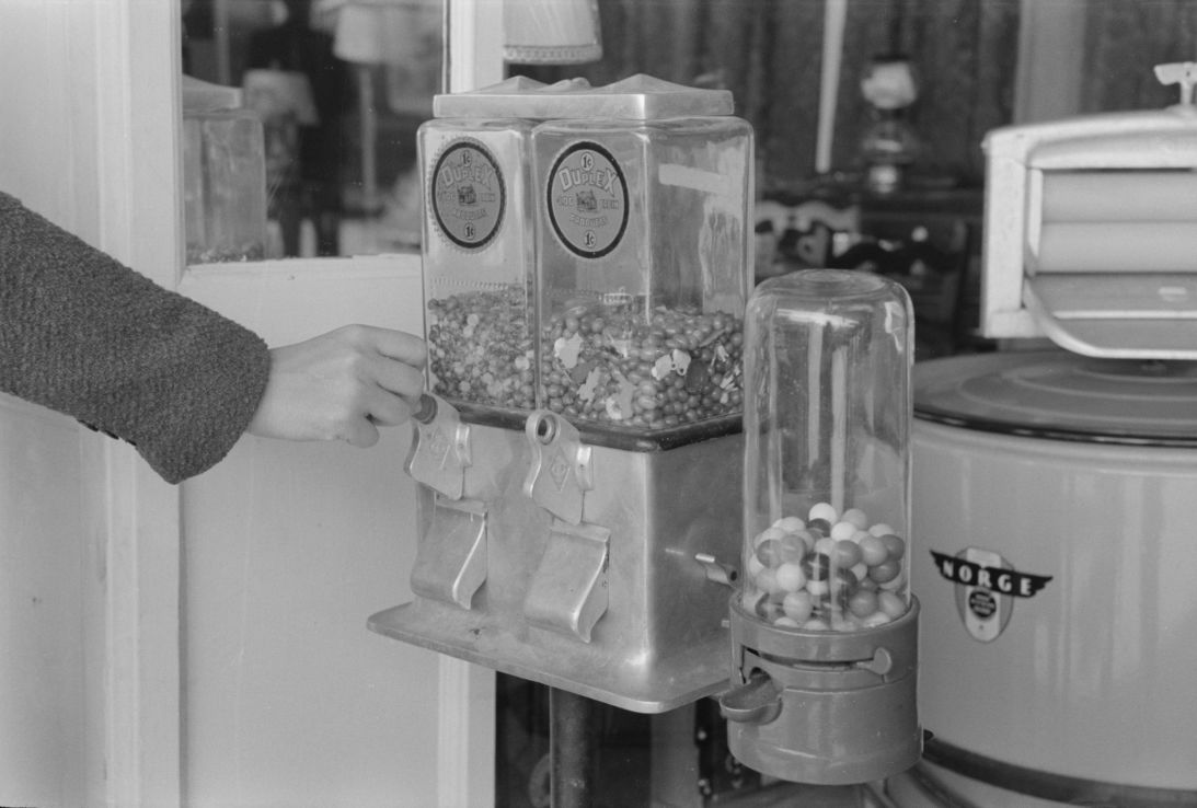 A customer inserts a penny into a candy machine in San Antonio, Texas, March 1939.