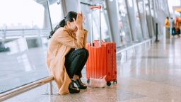 Young Asian businesswoman sad and unhappy at the airport with flight canceled.