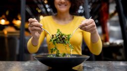 Healthy Latin American woman eating a salad at a restaurant - food and drinks concepts