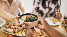 A cropped photo of an anonymous African-American female holding a bowl of  healthy salad.