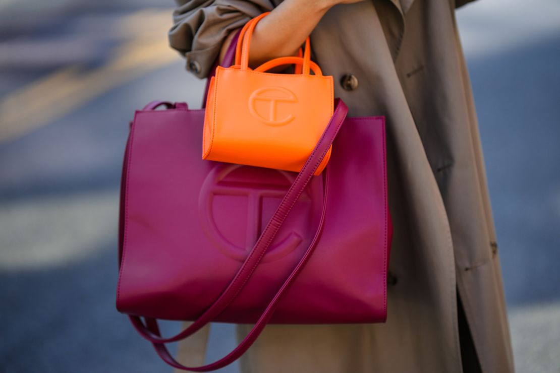 Samia Laaboudi wears a beige trench coat, a neon orange handbag from Telfar and a burgundy handbag from Telfar, during New York Fashion Week, on September 14, 2022 in New York City.