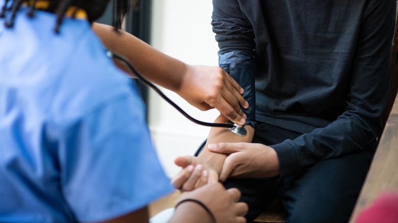 A nurse of takes the blood pressure of a teenage boy