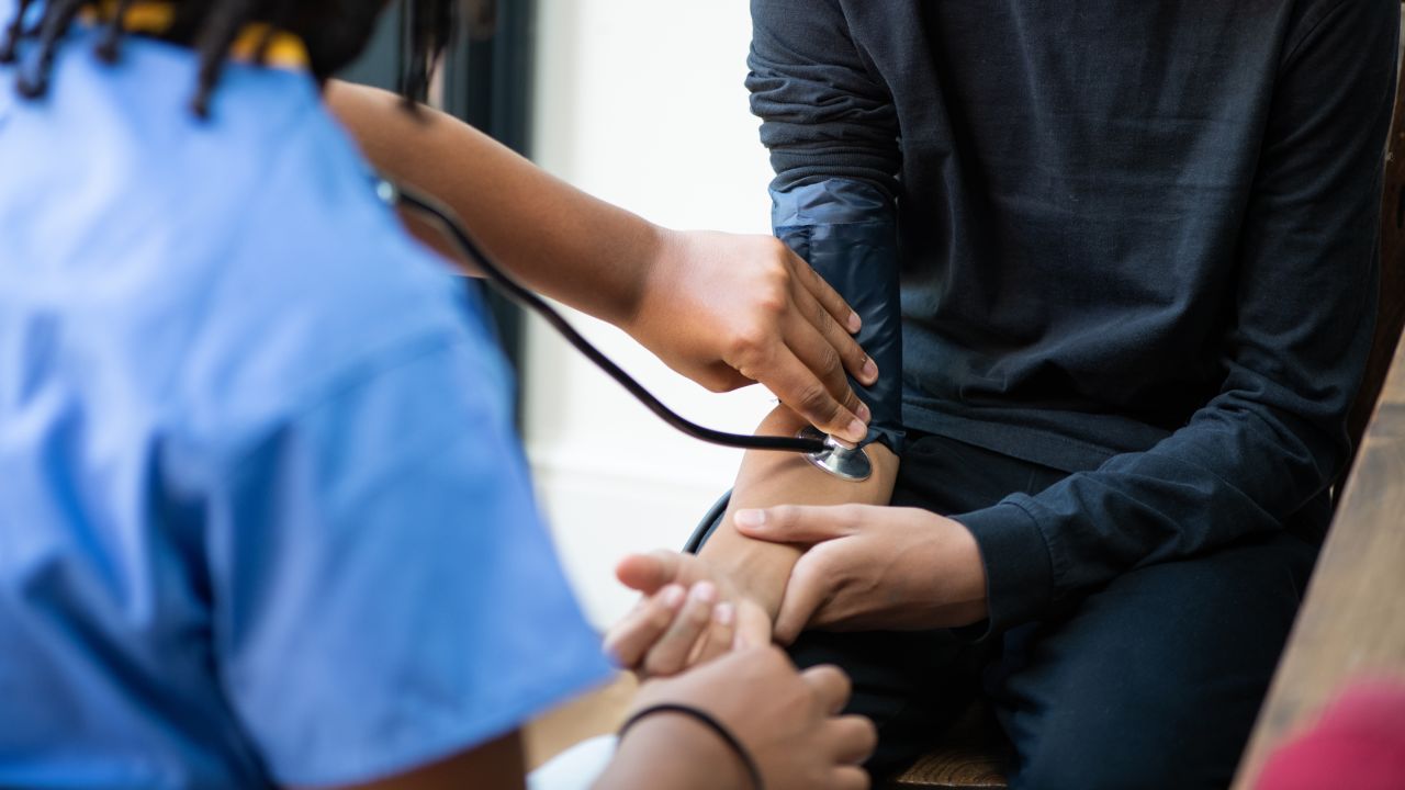 A nurse of takes the blood pressure of a teenage boy