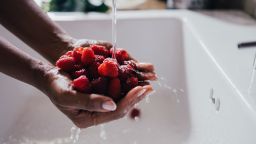 A cropped photo of an anonymous female holding organic fruit under water after their harvest.