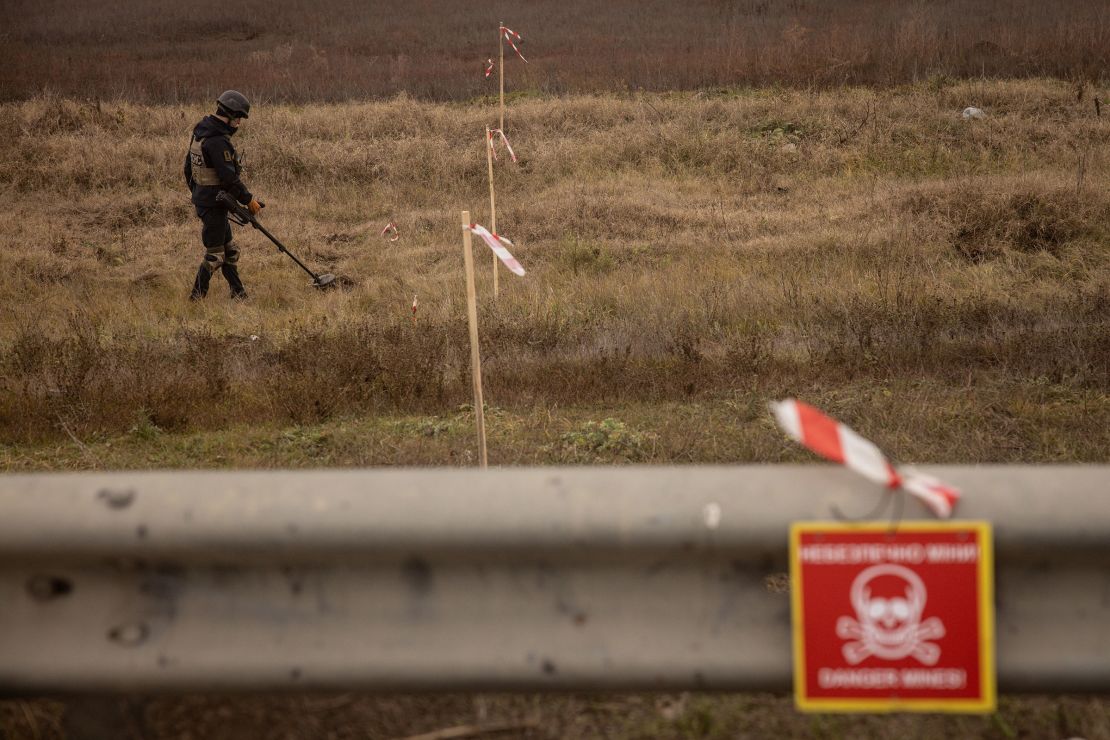 A member of a demining team works to clear mines and unexploded ordnance from the side of the main road leading to Kherson City in November 2022.
