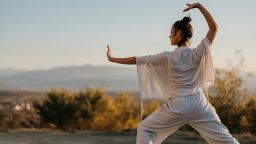 Woman practicing tai chi chuan on a meadow in sunset, in nature alone. Chinese management skill Qi's energy.