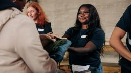 Smiling volunteer giving clothes to homeless woman at community center