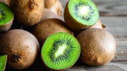 Ripe fruits of kiwi cut and whole on a wooden background, close -up.