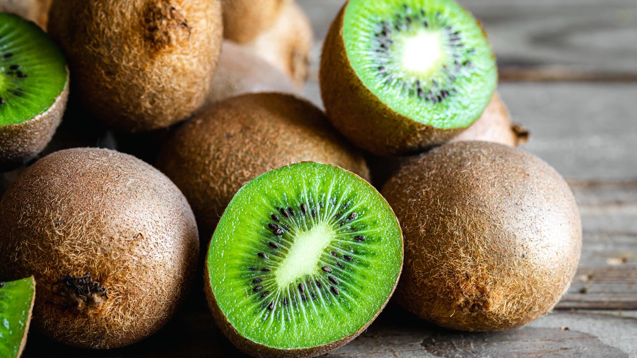 Ripe fruits of kiwi cut and whole on a wooden background, close -up.