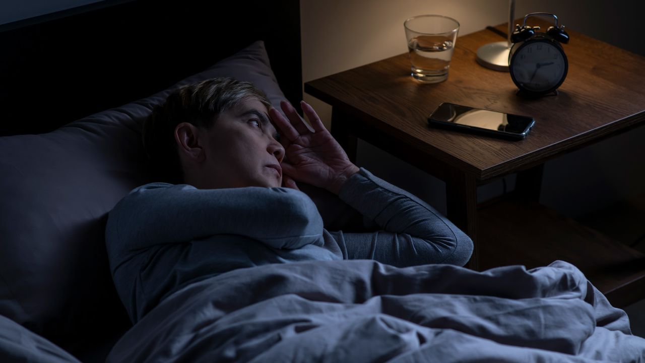 Depressed senior woman lying in bed cannot sleep from insomnia