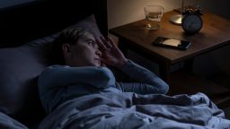 Depressed senior woman lying in bed cannot sleep from insomnia
