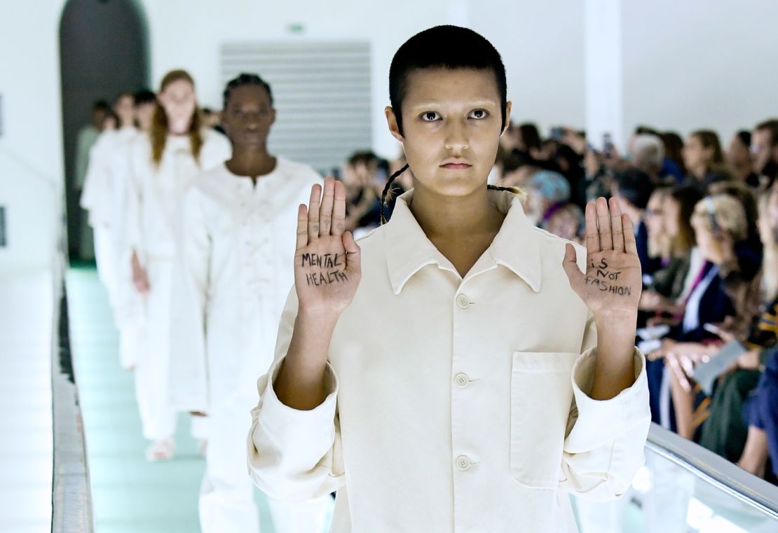 At the Gucci show in 2019, Ayesha Tan-Jones protested the label's straitjacket-inspired clothes by writing "Mental health is not fashion" on their hands.