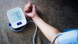 Asian Woman self blood pressure and heart rate measurement on blood pressure monitor recording the data at home
