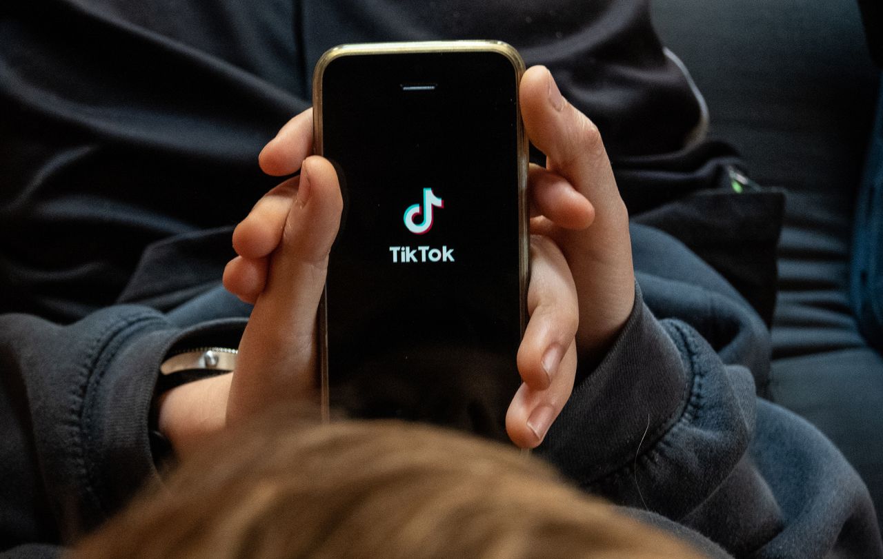 A boy looks at the TikTok app on a smartphone screen.