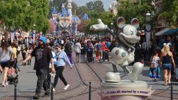 ANAHEIM, CA - APRIL 11: People walk next to Mickey Mouse along Main Street in front of the Sleeping Beauty Cast at the Disneyland theme park on April 11, 2023, in Anaheim, California. (Photo by Gary Hershorn/Getty Images)