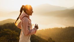 Female athlete jogging by the nature. Happiness and wellbeing, healthy lifestyle with physical activity. Pretty woman laughing when exercising with amazing sunrise view. Harmony with nature.