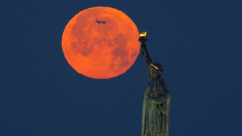 NEW YORK, NY - JUNE 04:  The full Strawberry Moon sets behind the Statue of Liberty before sunrise on June 4, 2023, in New York City.  (Photo by Gary Hershorn/Getty Images)
