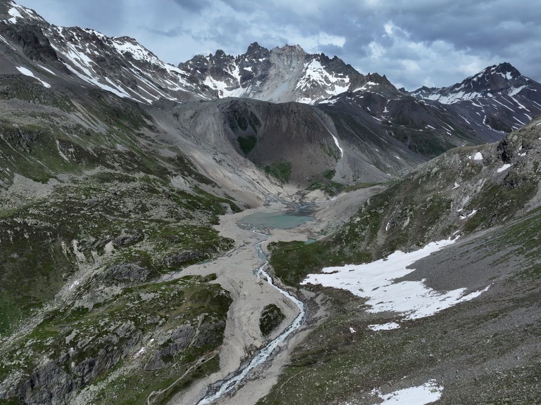 Partially collapsed Fluchthorn mountain (middle peak, grey) stands above a swath of rock and gravel deposited by its rockslide into the valley below on June 22, 2023 near Galtur, Austria.