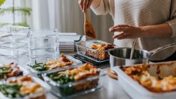 Woman weighing lunch boxes as part of healthy meal prep