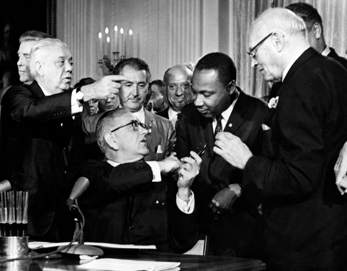 President Lyndon Johnson hands a pen to the Rev. Martin Luther King (second from right) after signing the Civil Rights Act in 1964 in the East Room of the White House.