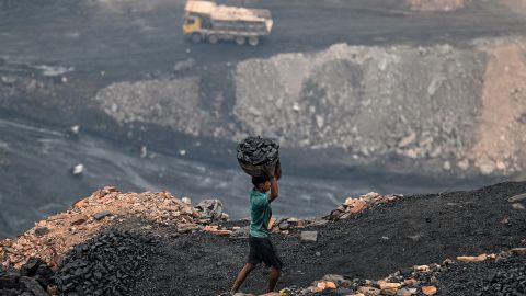 A coal picker carries coal from near an open cast mining site on the outskirts of Dhanbad on July 6, 2023. (Photo by Money SHARMA / AFP) (Photo by MONEY SHARMA/AFP via Getty Images)