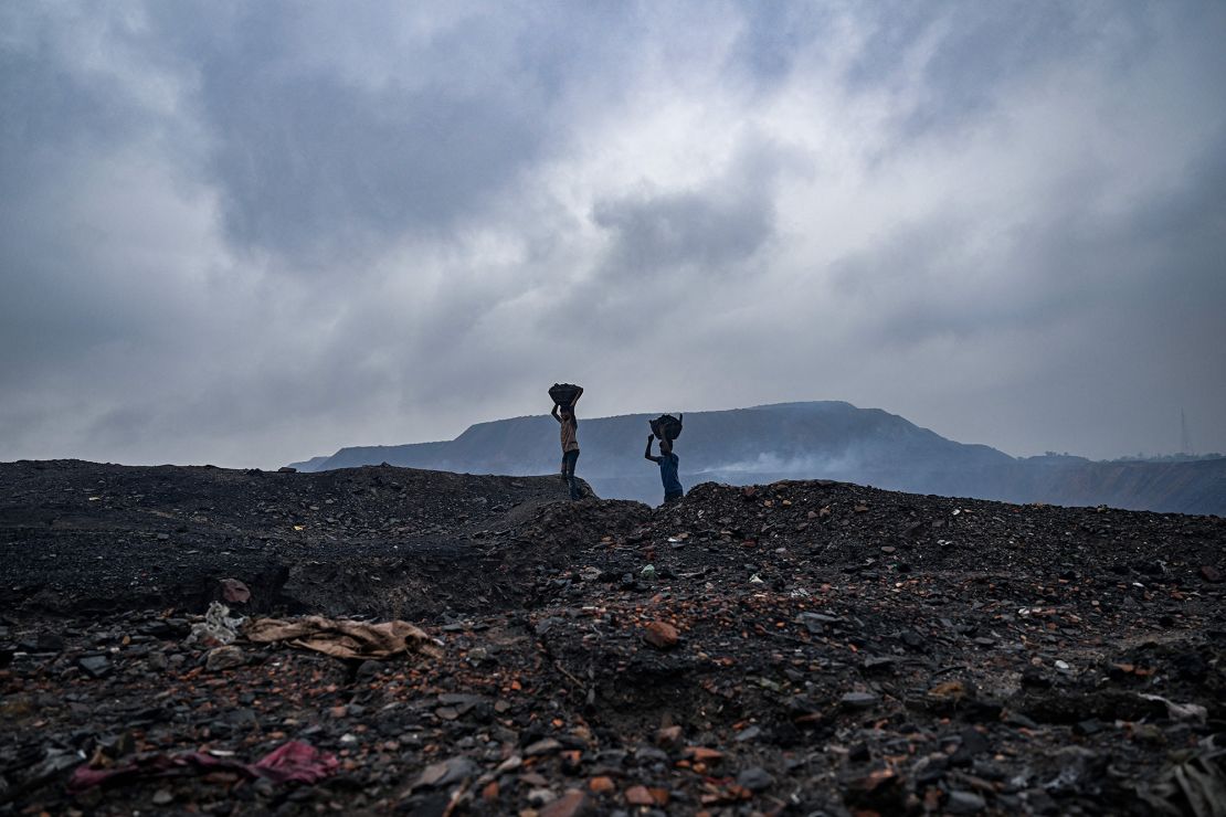 Coal pickers carry coal from near an open cast mining site on the outskirts of Dhanbad on July 6, 2023. India expects to double coal output by 2030.