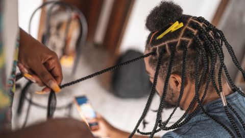 A man gets his hair braided