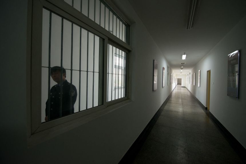 A guard watches from a hallway window inside Detention Center No. 1 during a government-guided tour in Beijing, October 25, 2012.