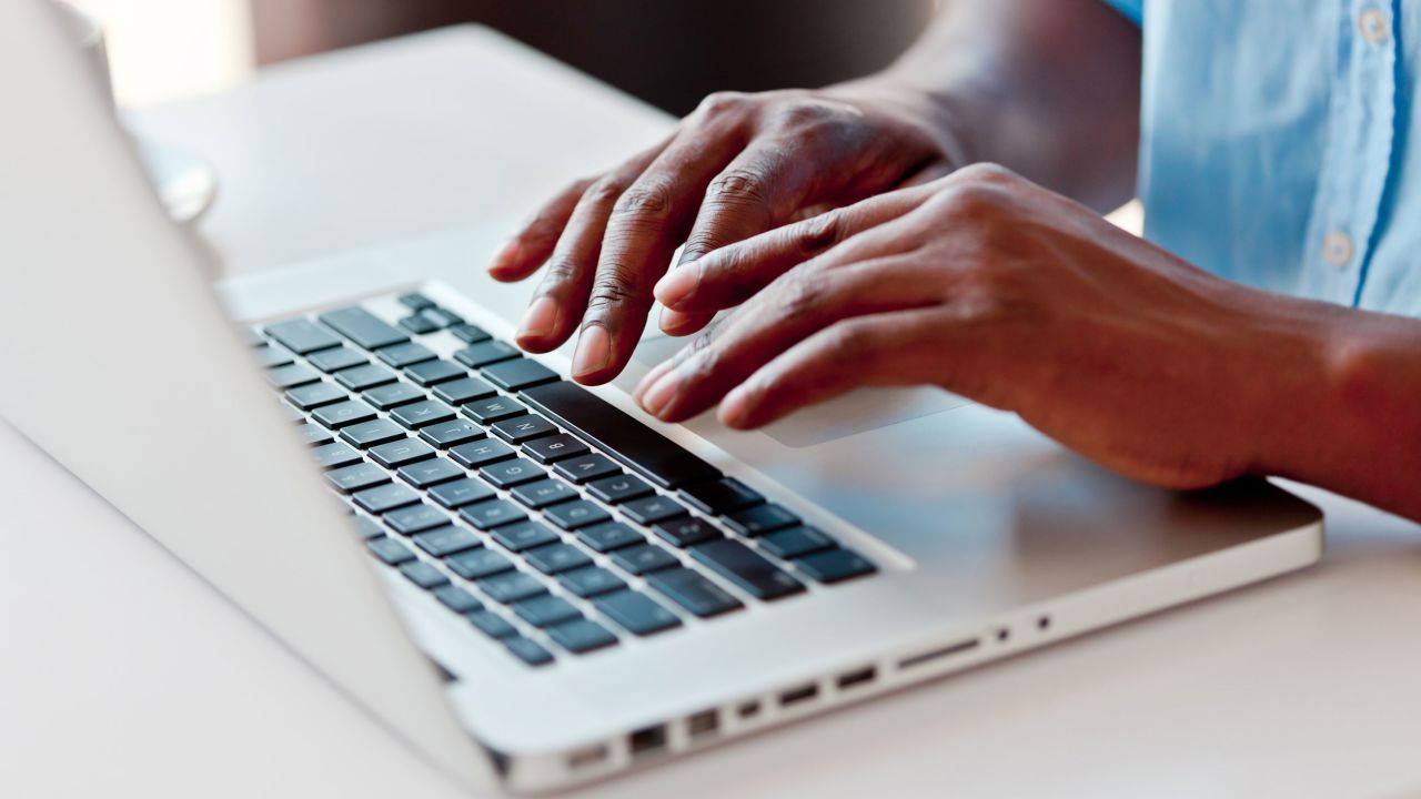 Close-up on male hands typing on laptop keyboard.