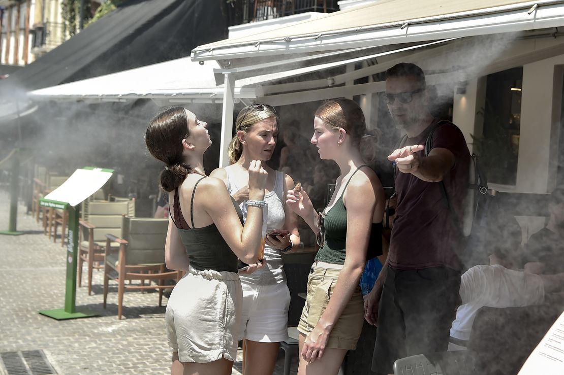 Tourists cool off under a mist of water during a heat wave on July 20, 2023 in Athens.