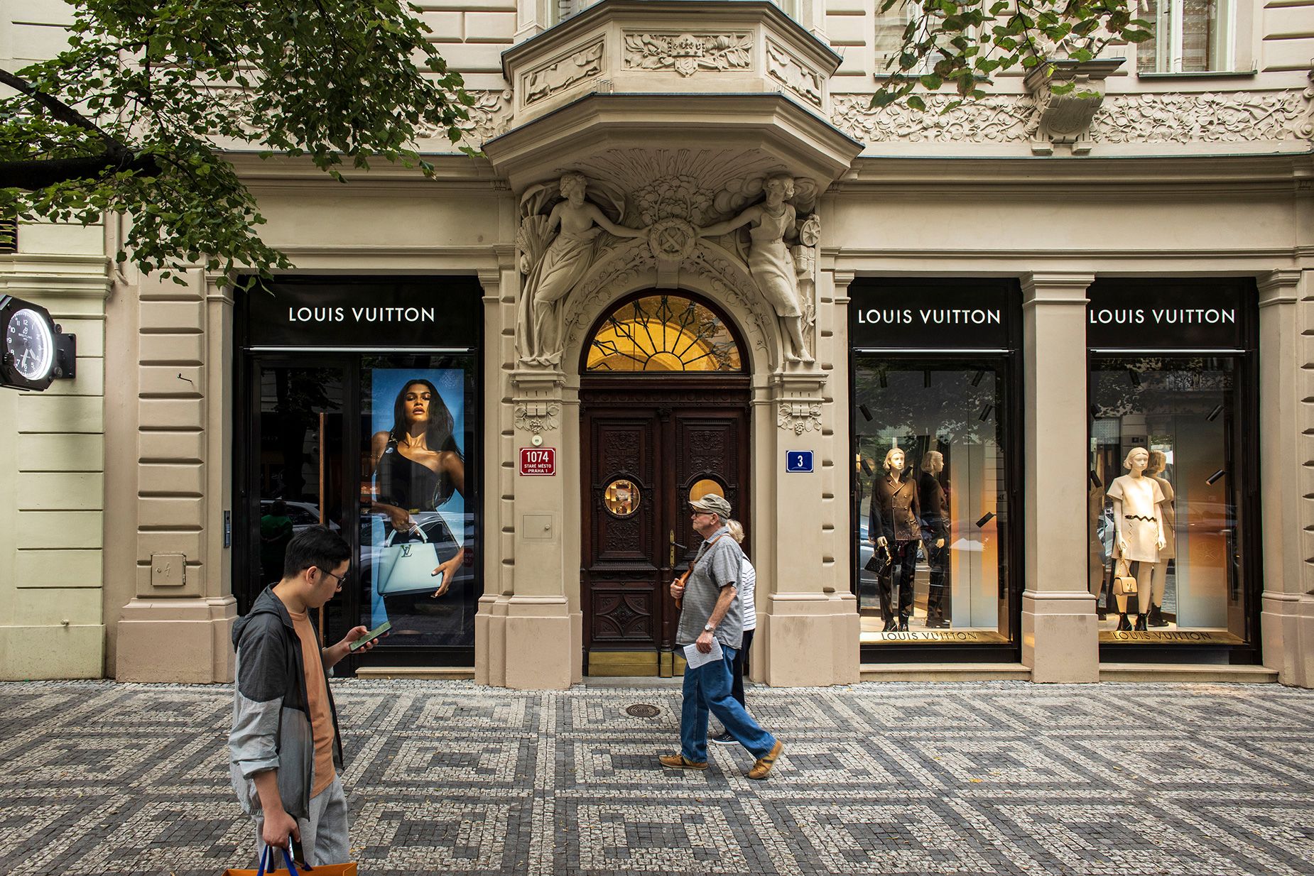 Pedestrians pass a Louis Vuitton luxury boutique on Parizska street in Prague, Czech Republic.