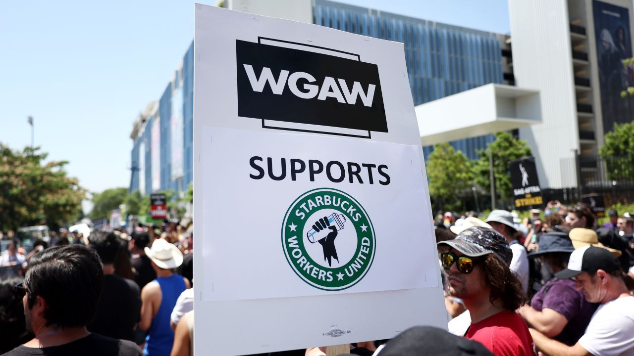 LOS ANGELES, CALIFORNIA - JULY 28: A sign reads 'WGAW Supports Starbucks Workers United' as Starbucks workers stand with striking SAG-AFTRA and Writers Guild of America (WGA) members on the picket line in solidarity outside Netflix studios on July 28, 2023 in Los Angeles, California. The show of support is part of a Starbucks Workers United ‘The Union is Calling’ summer bus tour across 13 cities in an effort to unionize more Starbucks stores with workers calling for a living wage and other protections amid a so-called ‘hot labor summer’. (Photo by Mario Tama/Getty Images)