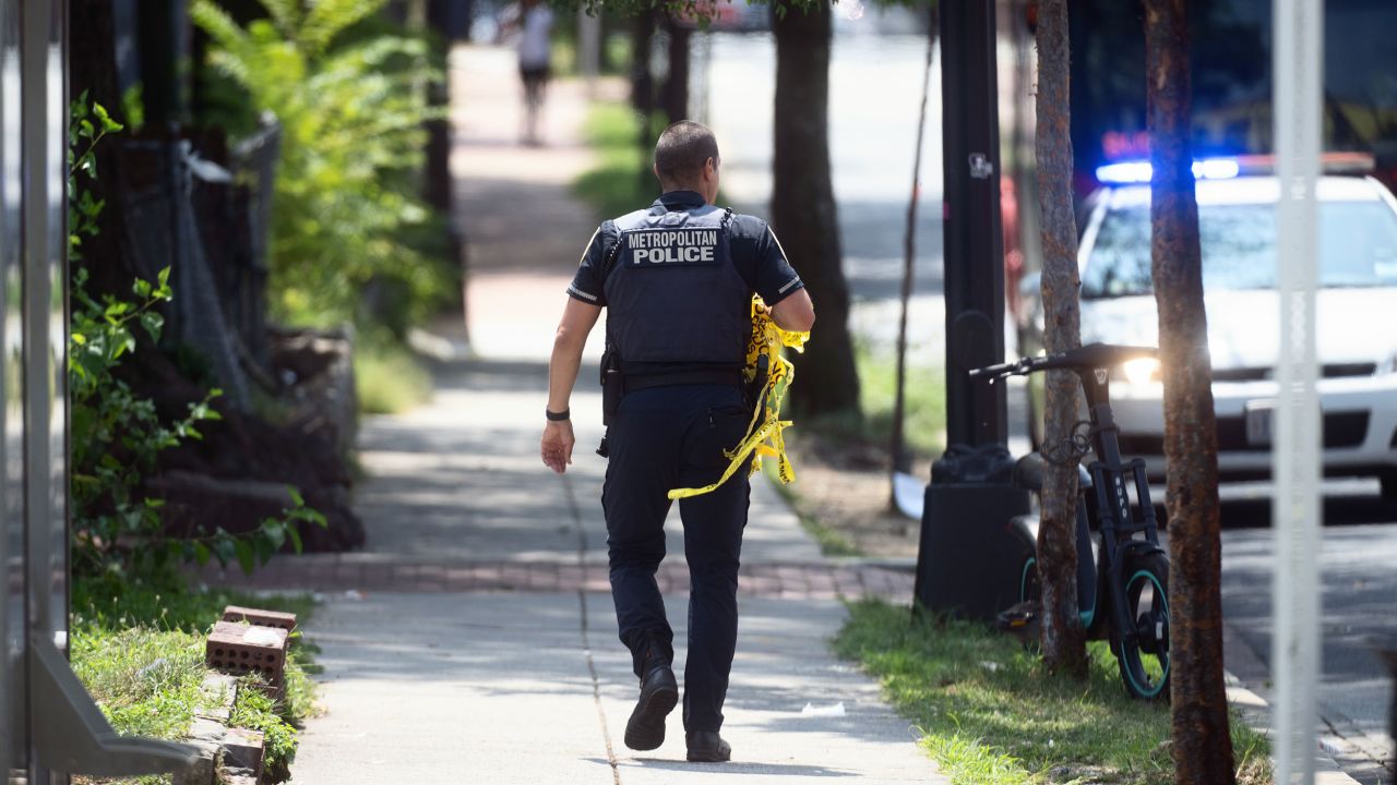 WASHINGTON, DC -AUGUST 06:   
 A police officer removes her police tape from a crime scene where people were shot the night before in Washington, DC on August 06, 2023.
Three people were shot and killed in an outbreak of gunfire in the Anacostia area of Southeast Washington Saturday night.  
 (Photo by Marvin Joseph/The Washington Post via Getty Images)
)