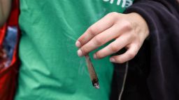 A participant holds a lit joint during the annual Hemp Parade on August 12, 2023 in Berlin, Germany.