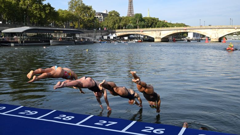 TOPSHOT - Athletes dive into the waters of the River Seine at the Alexander III Bridge, during the swim familiarisation event on the eve of planned triathlon test races in Paris, on August 16, 2023. The swim familiarisation event follows the cancellation on August 6 of the pre-Olympics test swimming competition due to excessive pollution which forced organisers to cancel the pre-Olympics event. From August 17 to 20, 2023, Paris 2024 is organising four triathlon events to test several arrangements, such as the sports operations, one year before the Paris 2024 Olympic and Paralympic Games. (Photo by Bertrand GUAY / AFP) (Photo by BERTRAND GUAY/AFP via Getty Images)