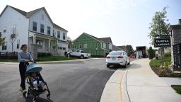 A person pushes a child in a stroller in a new housing development in Fairfax, Virginia, on August 22, 2023. Sales of homes in the United States ticked down in July, according to industry data released on August 22, 2023, as elevated mortgage rates and limited housing supply held buyers back. The housing market in the world's biggest economy has been reeling as interest rates climbed, making home owners reluctant to put their properties up for sale -- having earlier locked in lower rates on their mortgages.