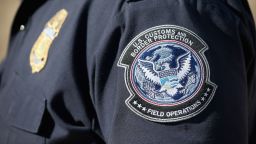 An officer from the US Office of Field Operations stands near the US-Mexico border.