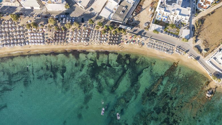 Aerial panoramic view from a drone of Agios Prokopios or Prokopi sandy beach in Naxos Island. Local Greeks and foreign tourists are protesting against the extensive occupation of the coast of umbrellas and sunbeds in the Greek islands and mainland, a growing nationwide movement against the expansion of expensive rented shadow. Beachbars are occupying larger areas than their permission which do not allow people to have free access to the beach. Similar incidents occurred in Agia Anna and Plaka beach. In Naxos the movement ''Save the beaches of Naxos now!'' emerged forming a legal complaint in the prosecutor similar to Paros Island with the media known name Towel Movement led to the government to bring inspectors.  Naxos is part of the Cyclades islands in the Aegean Sea, Greece on August 2023.