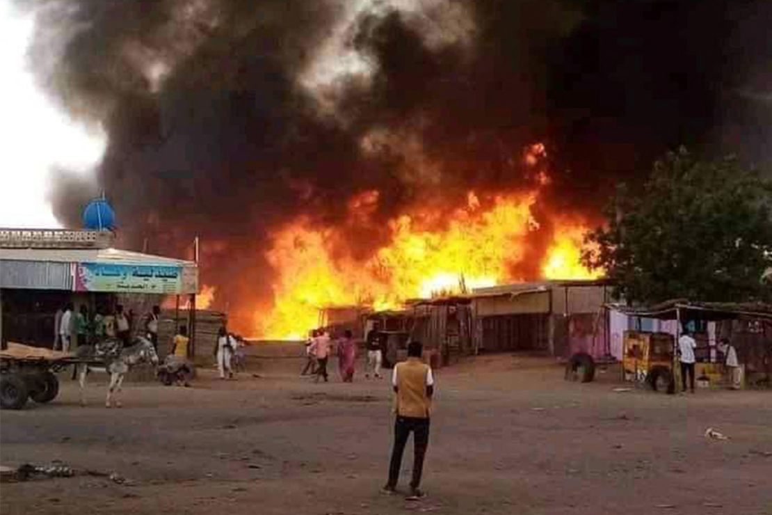 A man stands by as a fire rages in a livestock market area of El Fasher, in September 2023.