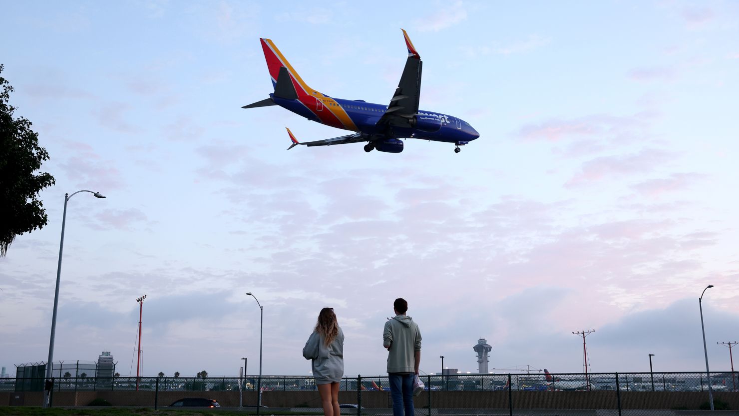 People view a Southwest Airlines plane landing from a park next to Los Angeles International Airport.