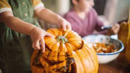 Happy children carving pumpkins on Halloween in autumn