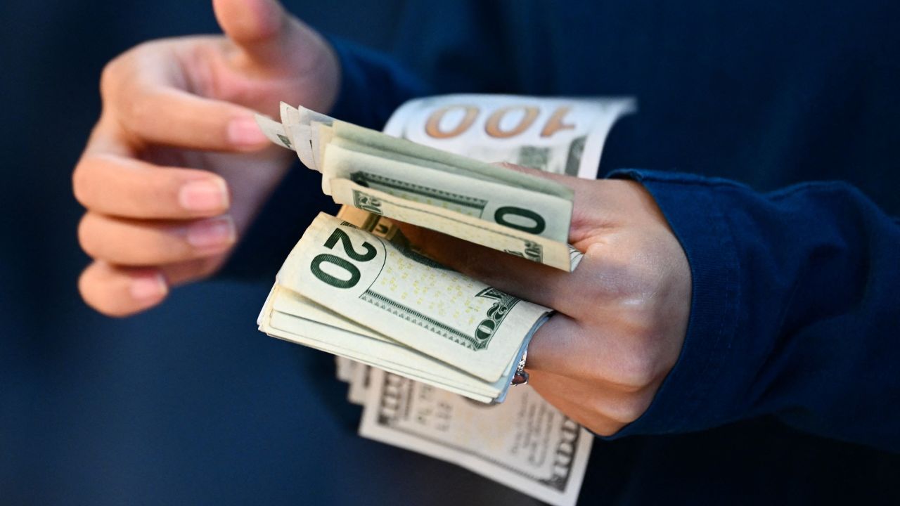 An employee counts US dollar currency as a customer pays cash for an Apple iPhone 15 series phone for sale at The Grove Apple retail store on release day in Los Angeles, California, on September 22, 2023. (Photo by Patrick T. Fallon / AFP) (Photo by PATRICK T. FALLON/AFP via Getty Images)