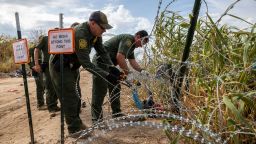 In this September 27 photo, US Border Patrol agents cut an opening through razor wire after immigrant families crossed the Rio Grande from Mexico in Eagle Pass, Texas.