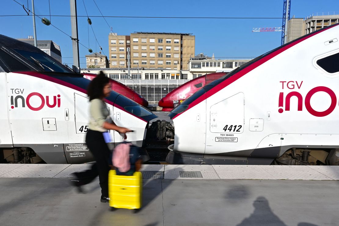 A passenger walks with luggage past a TGV speed train on the platforms of Paris' Gare du Nord station, on October 7, 2023.
