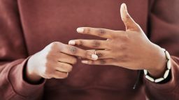 Wedding ring, hands and woman with divorce, decision and relationship doubt in her home. Jewelry, finger and female with marriage anxiety, commitment or fail in living room for choice regret in house