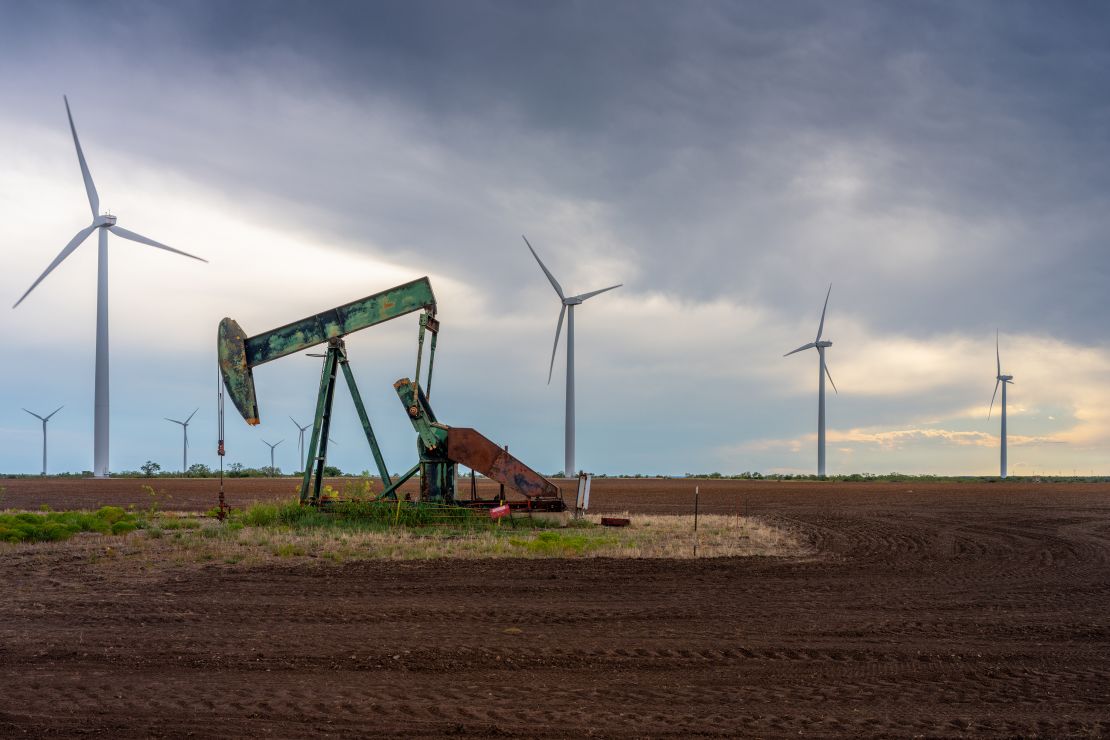 An oil pumpjack is seen near a field of wind turbines on October 4, 2023 in Nolan, Texas.